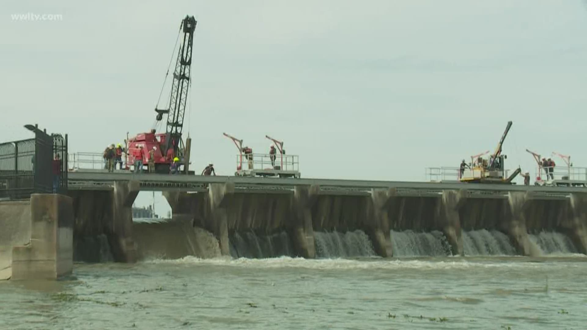 Friday, crews spent the morning lifting wooden pins allowing river water to flow through the spillway.